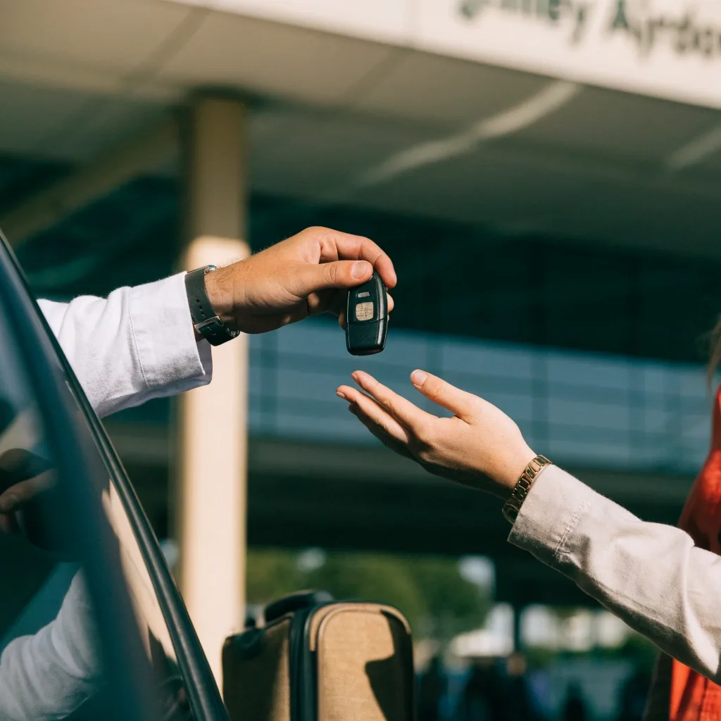 Driver handing car keys to valet attendant at airport podium